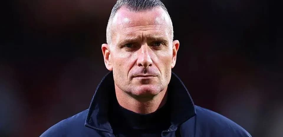 Coach standing with serious expression on the field