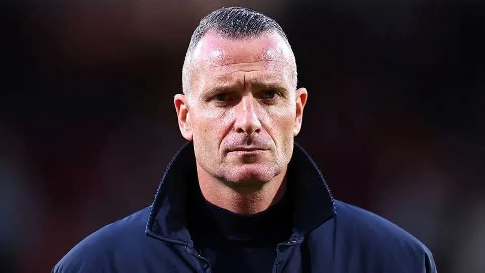Coach standing with serious expression on the field