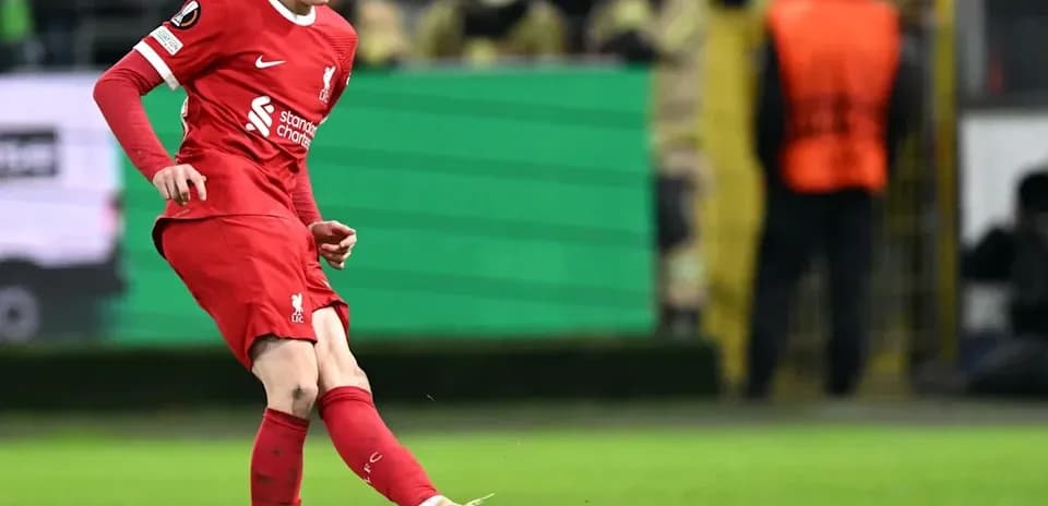 Player in red kicking a soccer ball on field