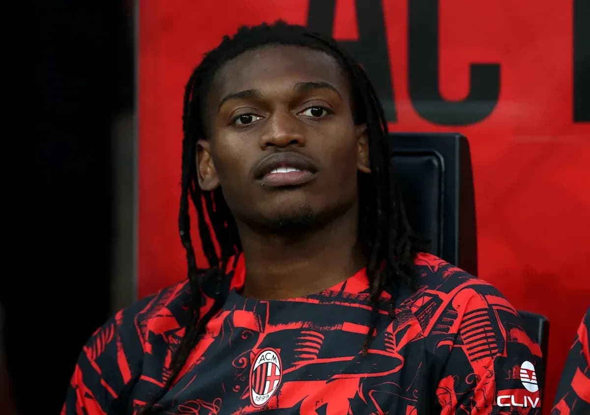 Player seated on bench wearing AC Milan jersey