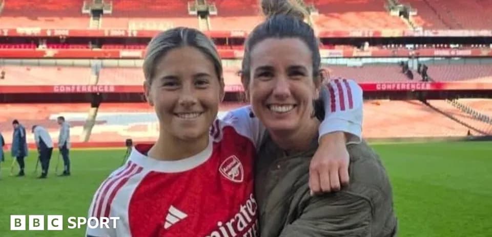 Two female football players posing at stadium