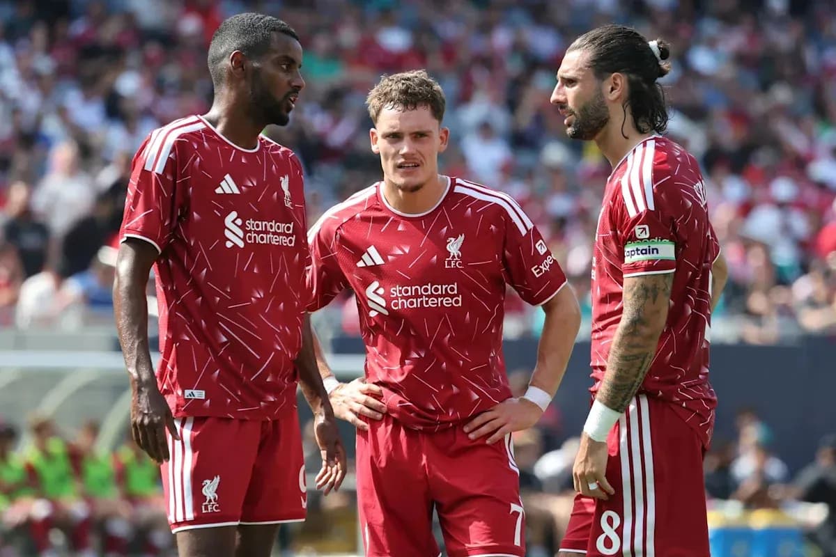 Three Liverpool players discussing on the field