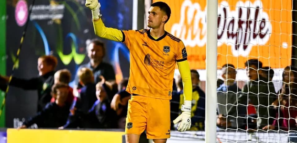 Goalkeeper signaling during a match with fans behind