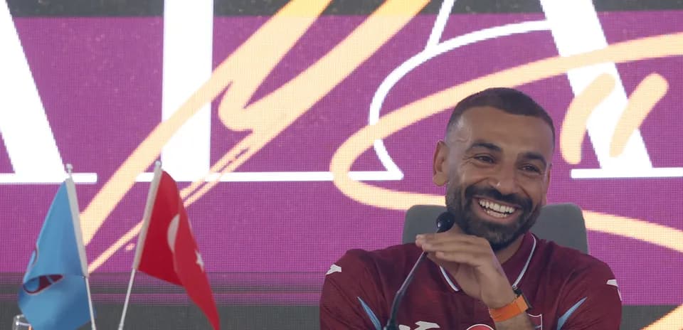 Player smiling at press conference with flags