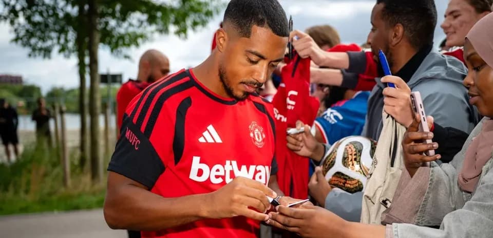 Player signing autographs for fans outside venue