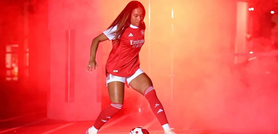 Player in Arsenal kit dribbling a soccer ball