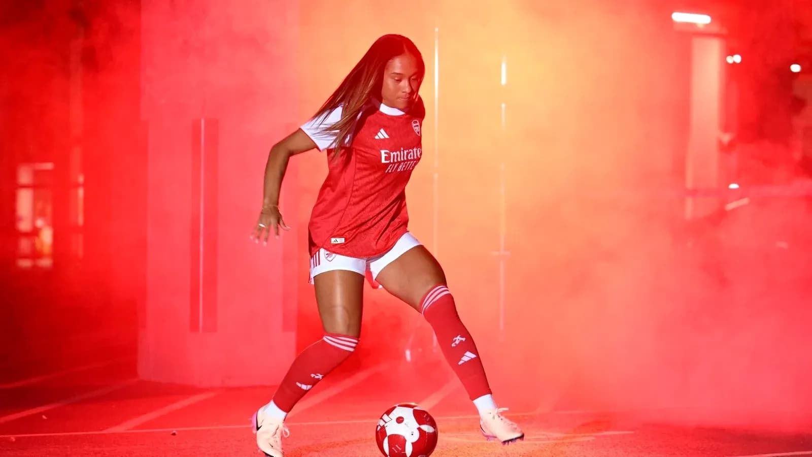 Player in Arsenal kit dribbling a soccer ball