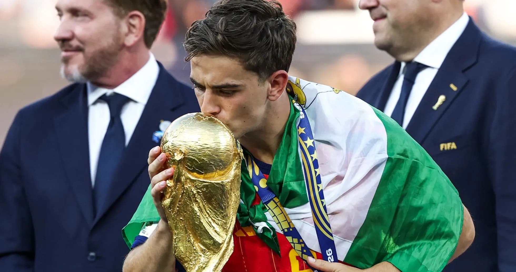 Player kissing World Cup trophy wearing national flag