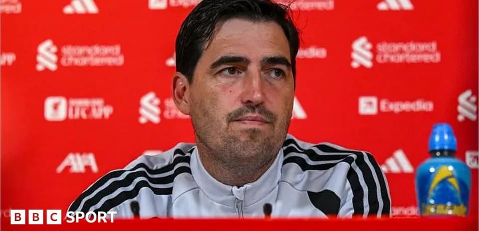 Manager speaking at press conference with red backdrop