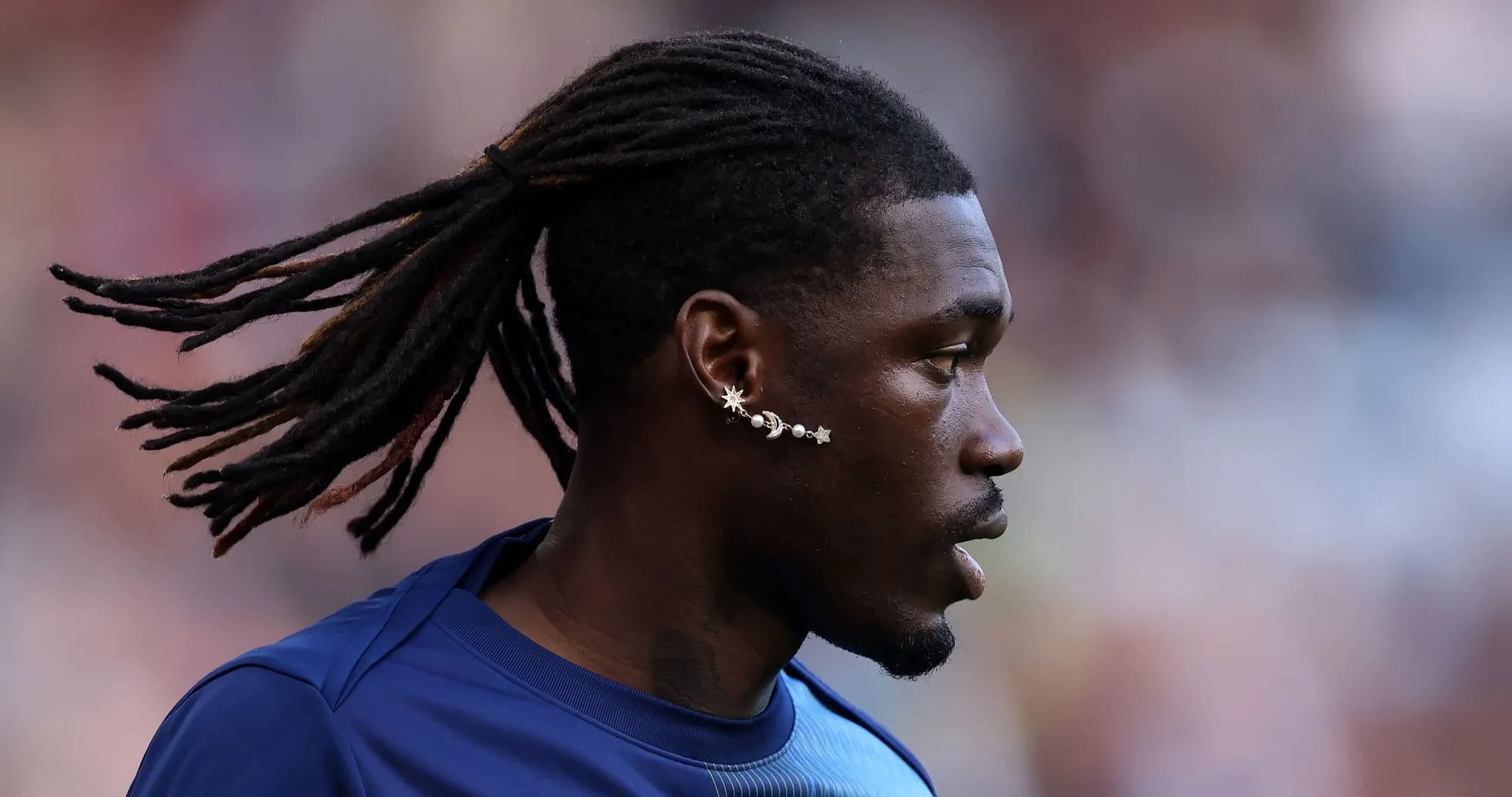 Player with dreadlocks and unique earring on field