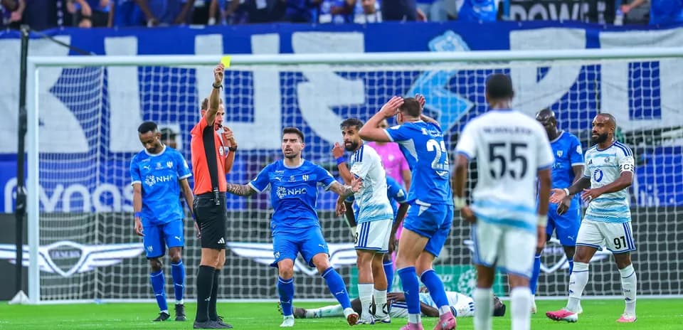 Referee showing yellow card during football match
