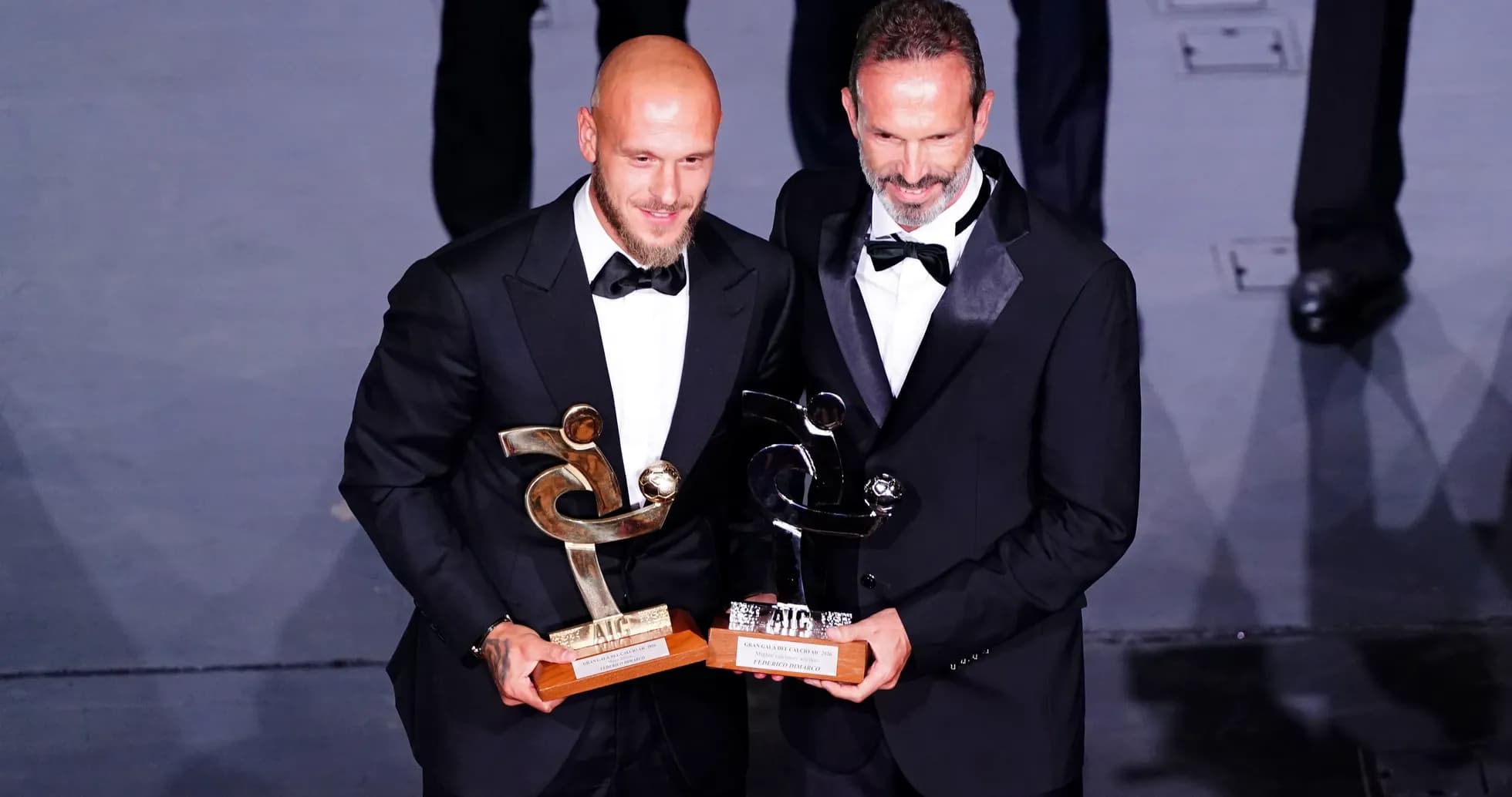 Two award winners holding trophies on stage