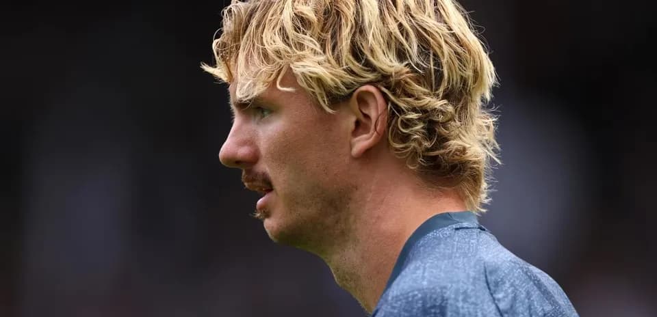 Player in profile with curly blonde hair and mustache
