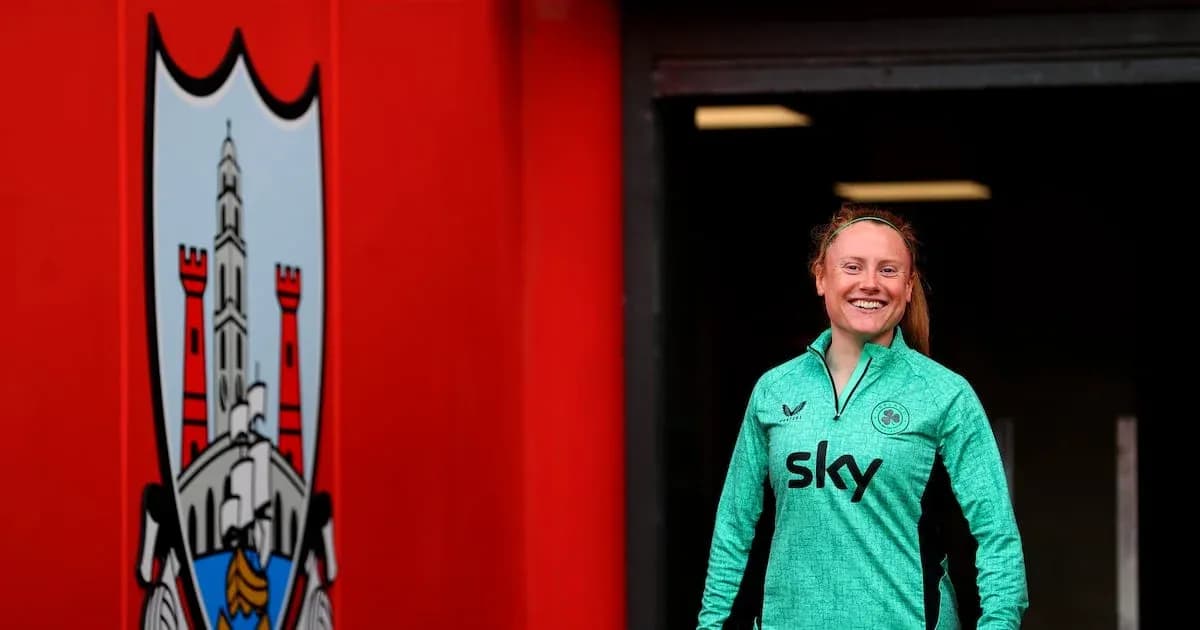 Player smiling in green kit near team logo