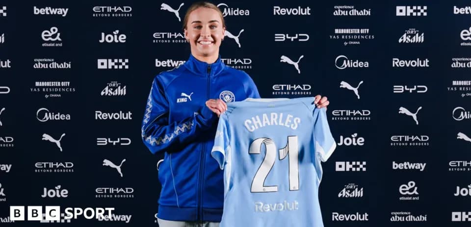 Player holding Manchester City jersey at signing event