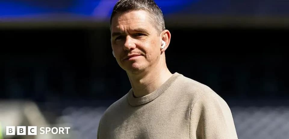 Person in beige sweater standing at stadium