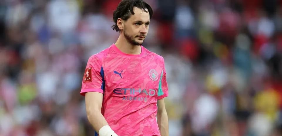 Goalkeeper in pink kit walking on the pitch