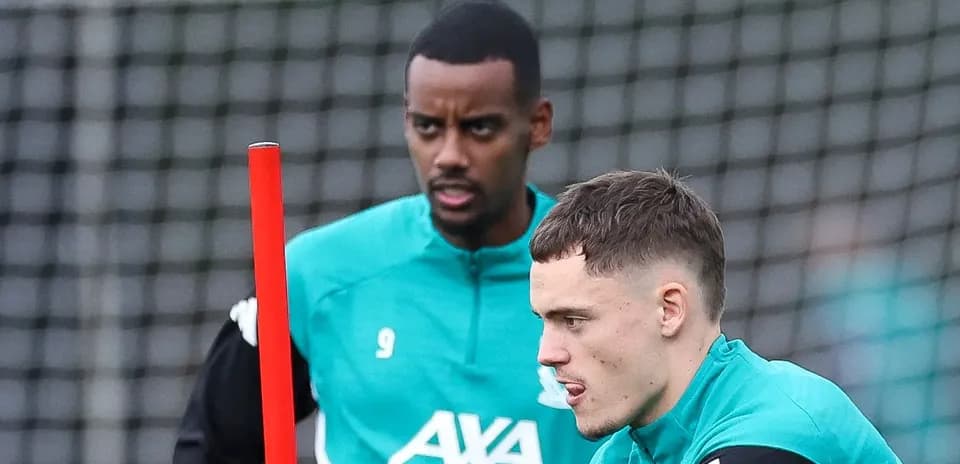 Two players training with a pole on the pitch