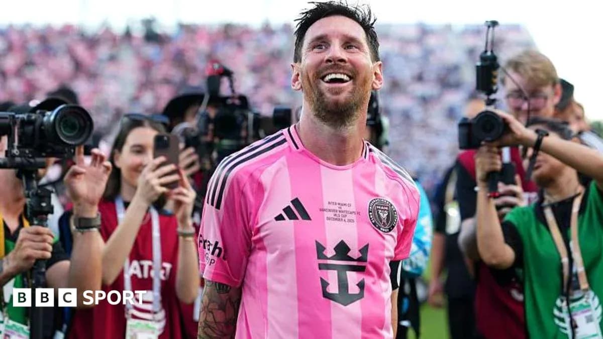 Lionel Messi smiling in pink jersey surrounded by fans