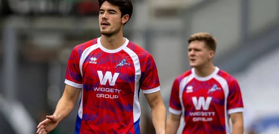 Players in red and blue jerseys walking on pitch