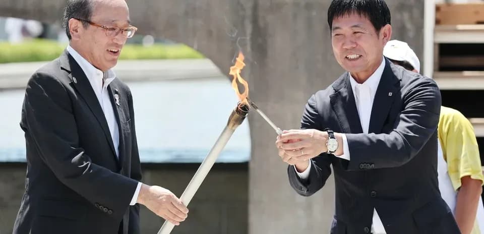 Two officials lighting a ceremonial torch together