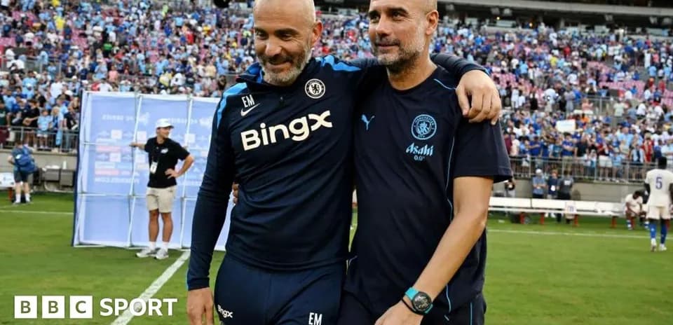Two coaches walking together on the pitch