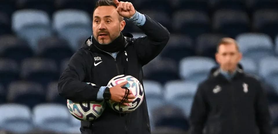 Coach instructing players while holding footballs