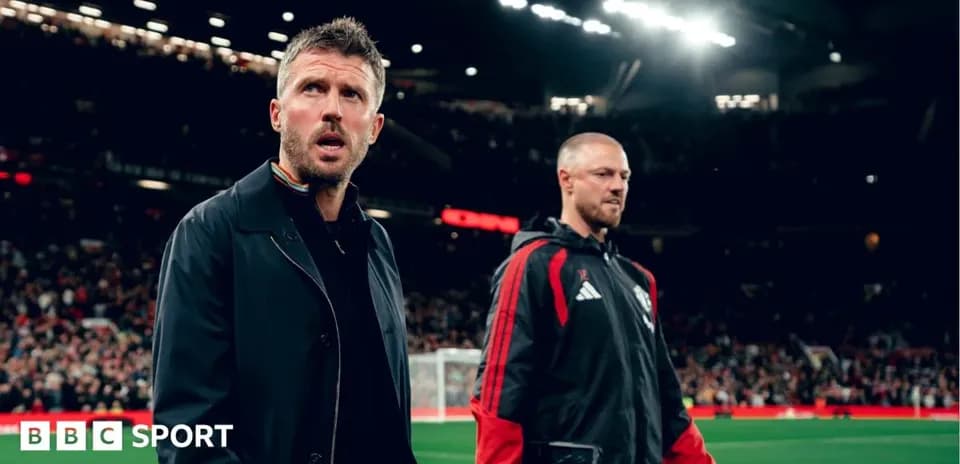 Two coaches walking on the pitch at Old Trafford