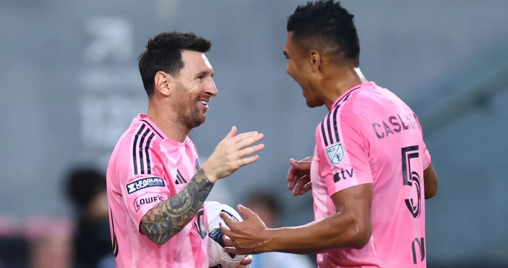 Two players celebrating a goal in pink jerseys
