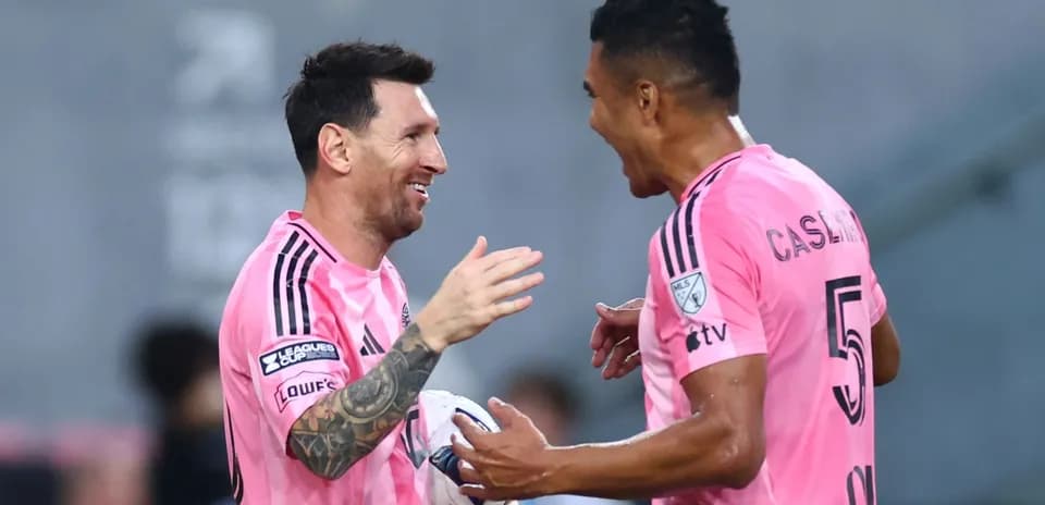 Two players celebrating a goal in pink jerseys