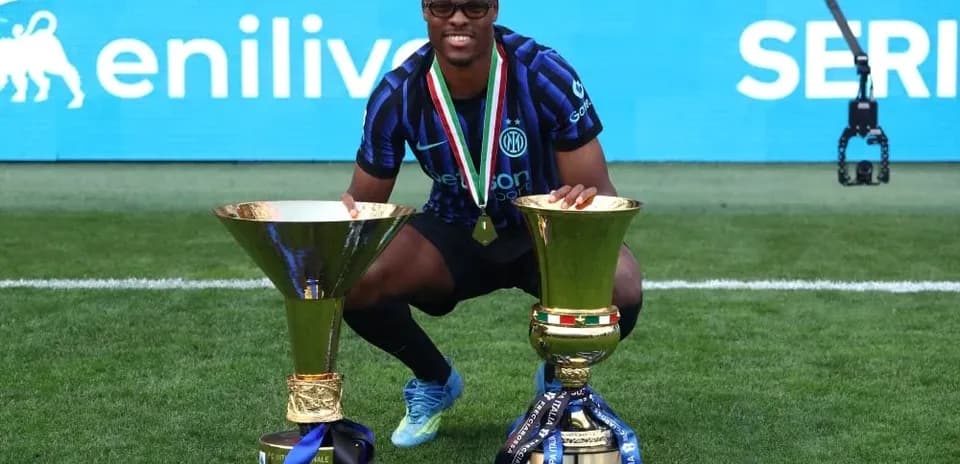Player celebrating with two trophies on field