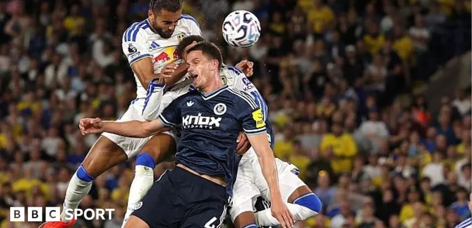 Players contesting a header during football match