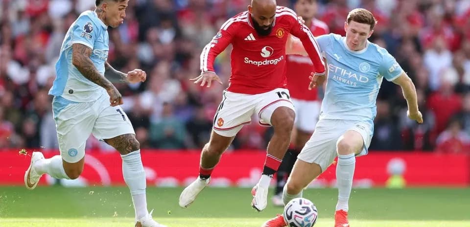 Manchester United player evading two Manchester City defenders