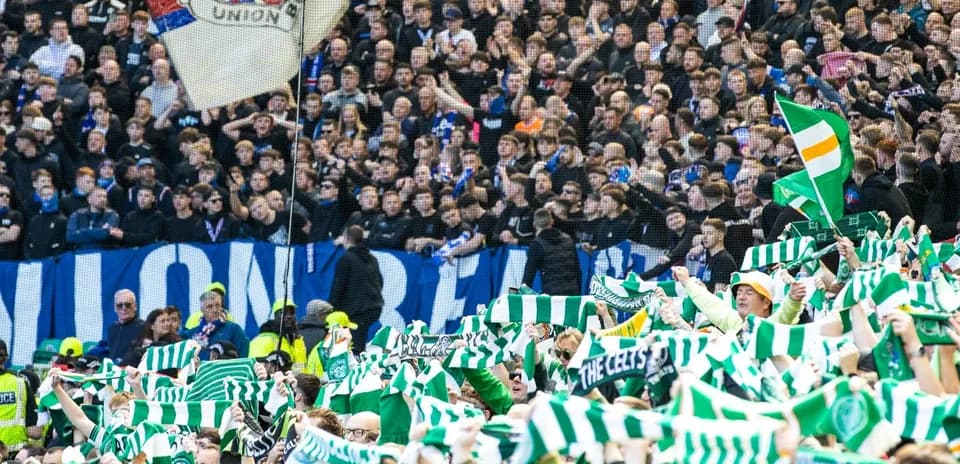 Fans waving green and white scarves in stadium