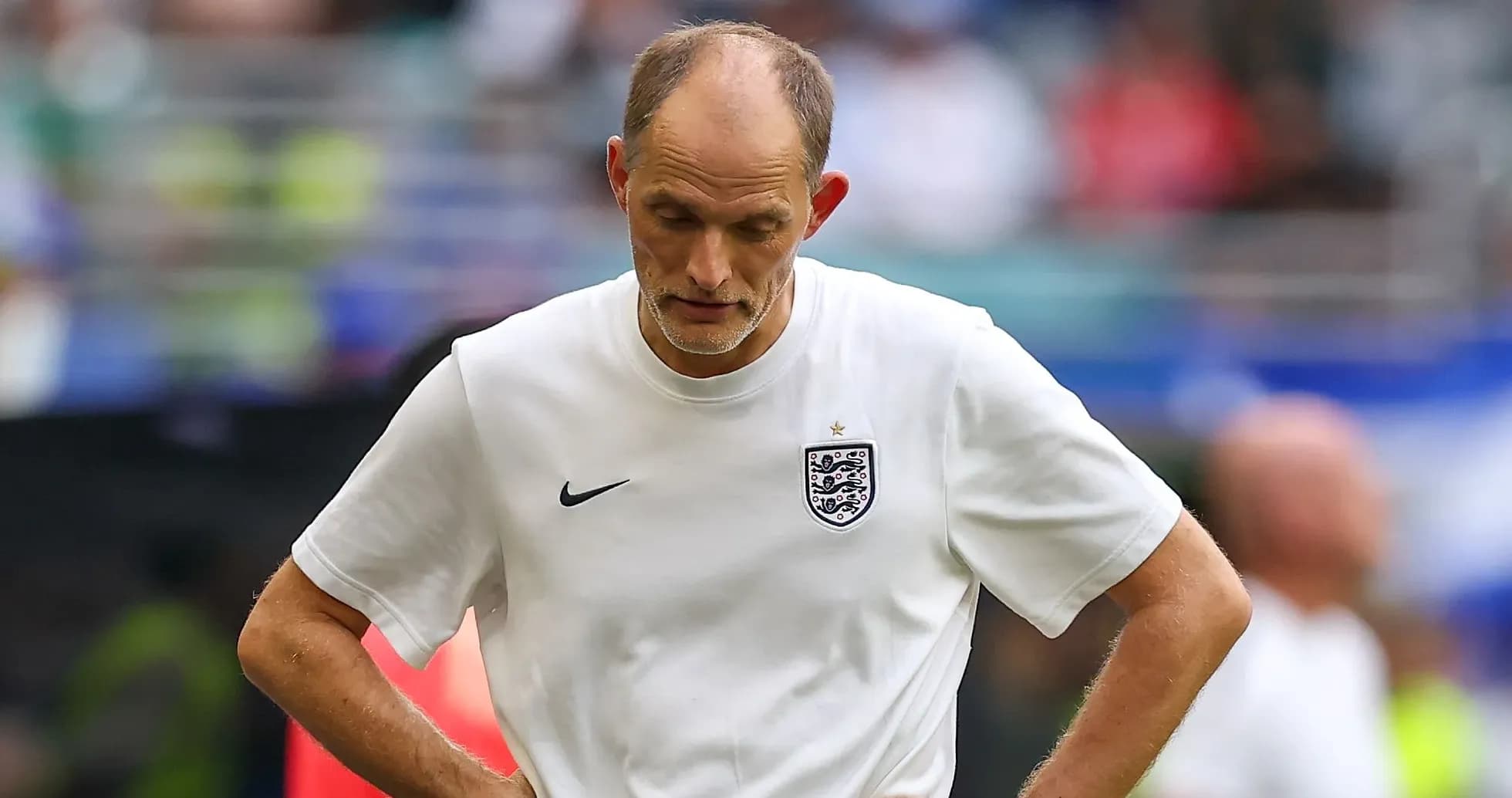 Coach walking on the pitch with downcast expression