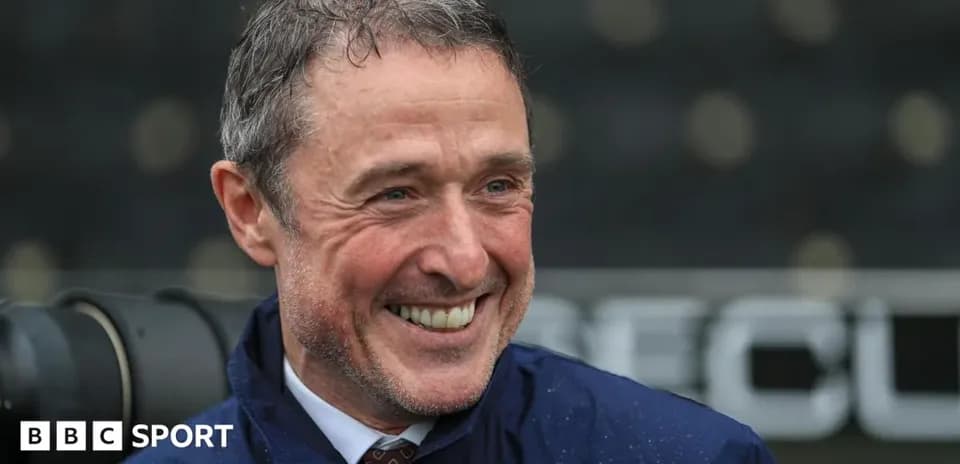 Smiling man in a jacket at a sports venue