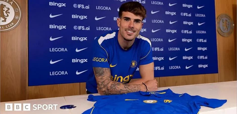 Player posing with Chelsea shirt at press conference