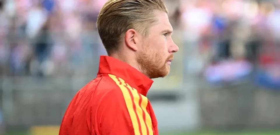 Player in red jersey looking on from sidelines