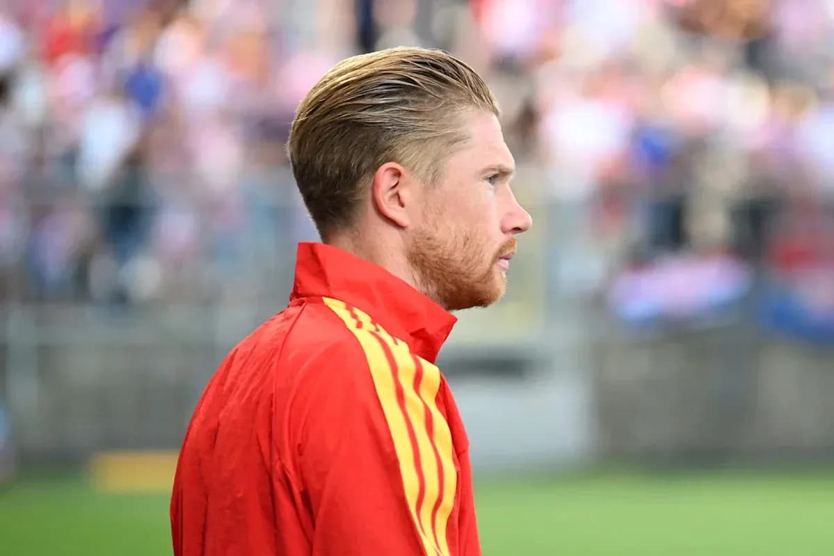 Player in red jersey looking on from sidelines