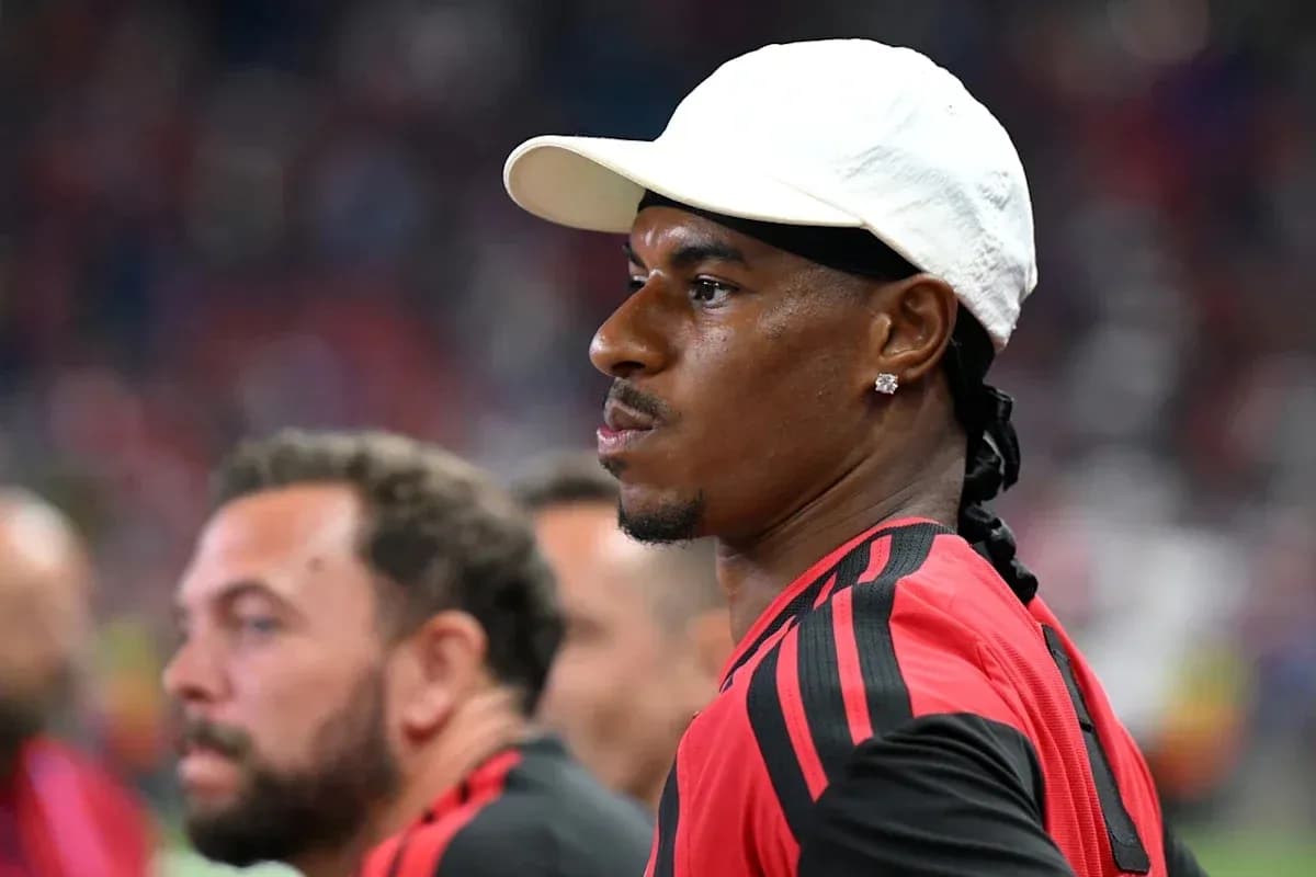 Player in red jersey observing from the sidelines
