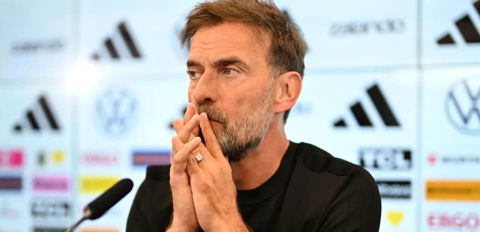 Manager speaking at press conference with logos in background