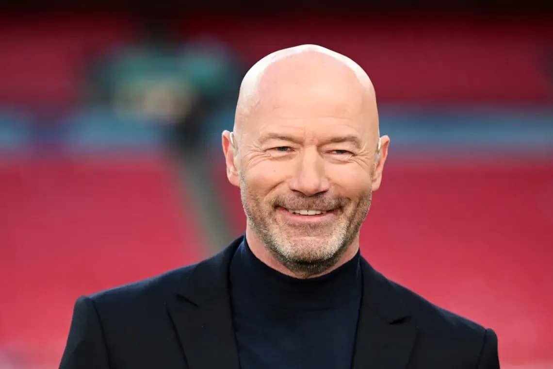 Man smiling in a suit at stadium