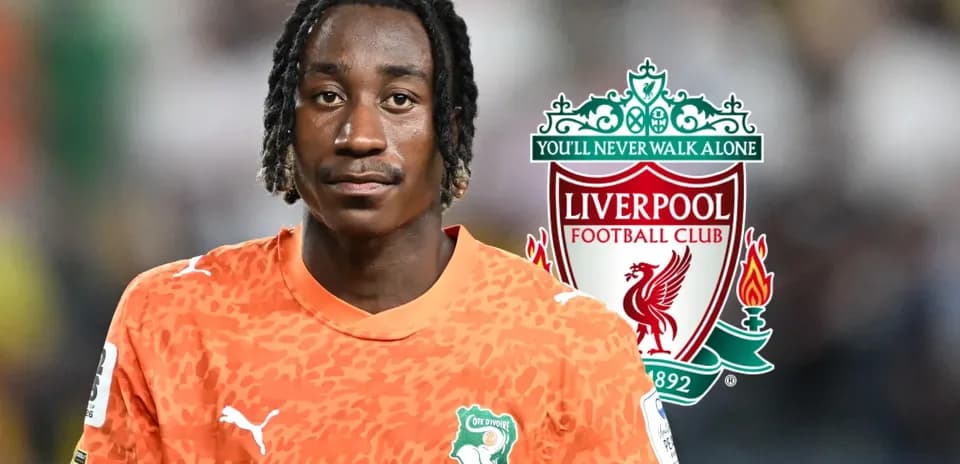 Goalkeeper in orange jersey with Liverpool logo backdrop