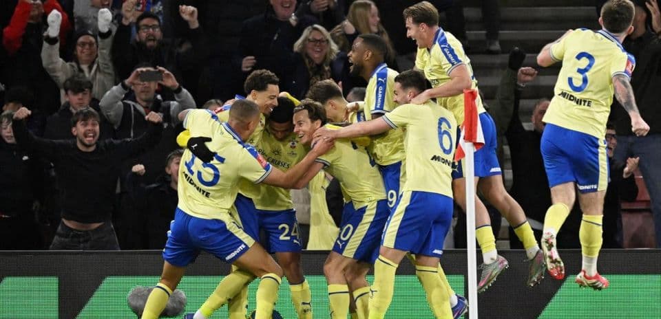 Players celebrating a goal with fans in background