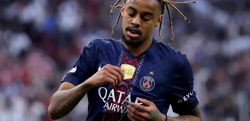 Player inspecting medal after match in PSG jersey