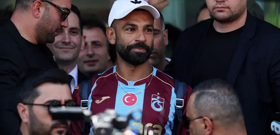 Player in Trabzonspor jersey surrounded by security personnel