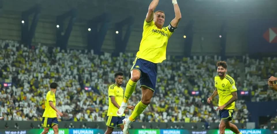 Player celebrating a goal with teammates on pitch