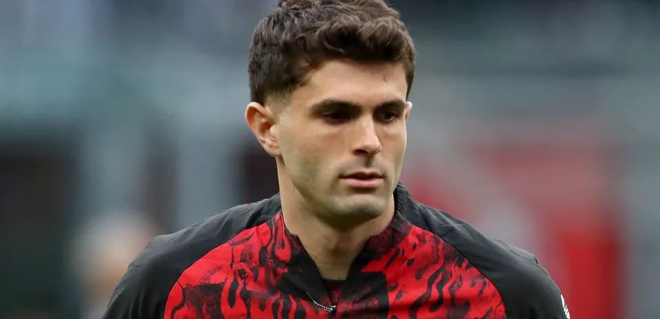 Player in AC Milan jersey walking on pitch
