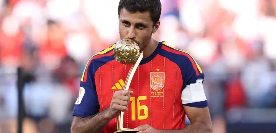 Player in Spain jersey holding trophy after victory