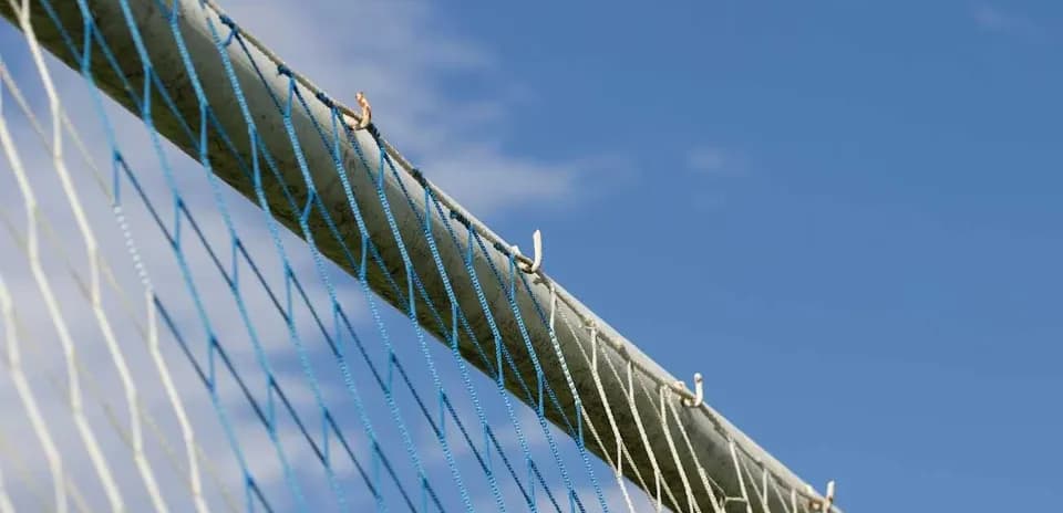 Close-up of soccer goal net against blue sky